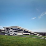 A modern-looking museum building surrounded by grass and embedded into a hillside.