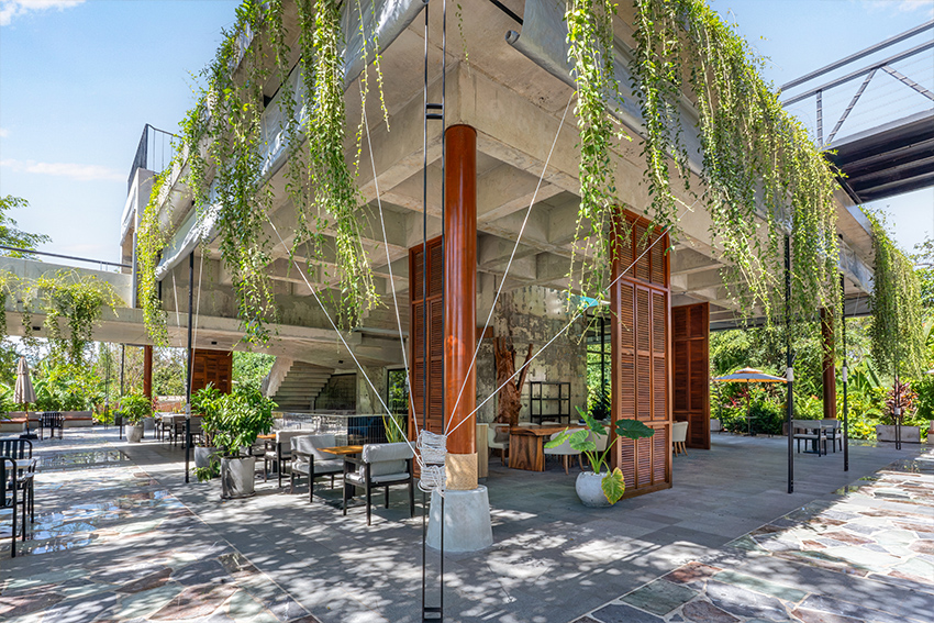 unfinished concrete structure turns into nature-filled tropical café in cambodia